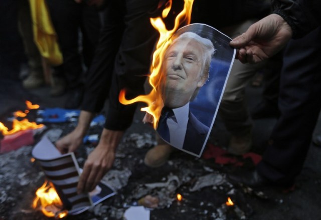 A portrait of US President Donald Trump burns during a demonstration in the capital Tehran on December 11, 2017 to denounce his declaration of Jerusalem as Israel's capital. / AFP PHOTO / ATTA KENARE