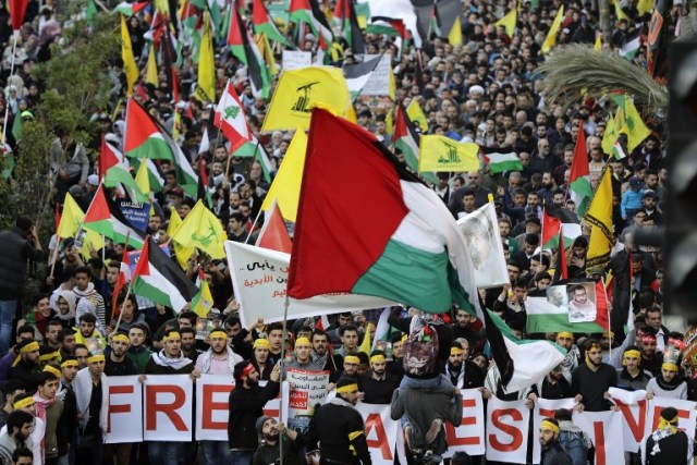 Supporters of Lebanon's Hezbollah Shiite movement wave national, Palestinian (front) and Hezbollah's yellow flags during a massive rally in the Lebanese capital Beirut on December 11, 2017 to protest US President Donald Trump's controversial recognition of Jerusalem as Israel's capital.  / AFP PHOTO / Joseph EID