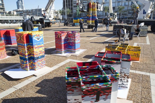 Workers and volunteers help assemble bricks during the construction of a LEGO tower in Tel Aviv's Rabin Square on December 26, 2017, as the city attempts to break Guinness world record of the highest such structure. / AFP PHOTO / JACK GUEZ
