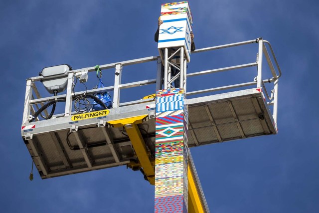 A man helps fix the top of a LEGO tower under construction in Tel Aviv on December 27, 2017, as the city attempts to break Guinness world record of the highest such structure. / AFP PHOTO / JACK GUEZ