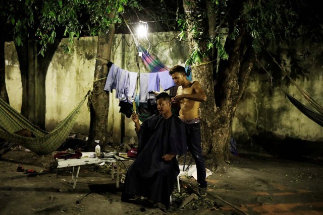 A Venezuelan man cuts hair of his friend at a gym which has turned into a shelter for Venezuelans and is run by Civil Defense with meals provided by Evangelical churches in Caimbe neighbourhood in Boa Vista, Roraima state, Brazil November 17, 2017. REUTERS/Nacho Doce SEARCH "VENEZUELAN MIGRANTS" FOR THIS STORY. SEARCH "WIDER IMAGE" FOR ALL STORIES.