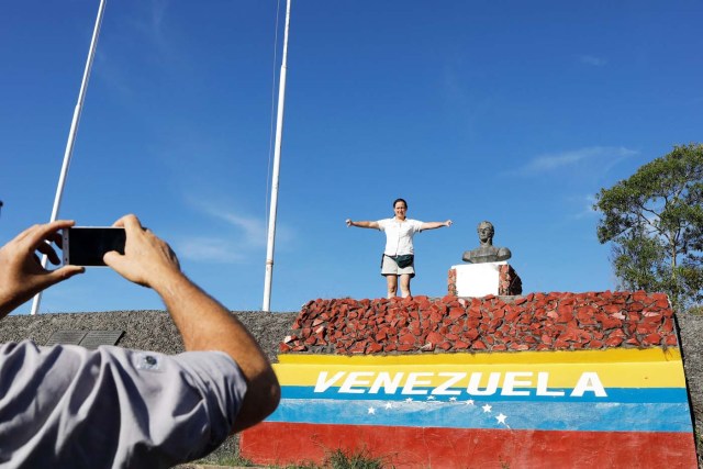 A Venezuelan man takes a picture of his wife as she gestures after they crossed the border from Venezuela into the Brazilian city of Pacaraima, Roraima state, Brazil November 16, 2017. REUTERS/Nacho Doce SEARCH "VENEZUELAN MIGRANTS" FOR THIS STORY. SEARCH "WIDER IMAGE" FOR ALL STORIES.