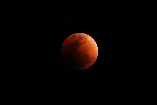 A "super blood blue moon" is seen during an eclipse, behind an office building in Hong Kong, China January 31, 2018.      REUTERS/Bobby Yip