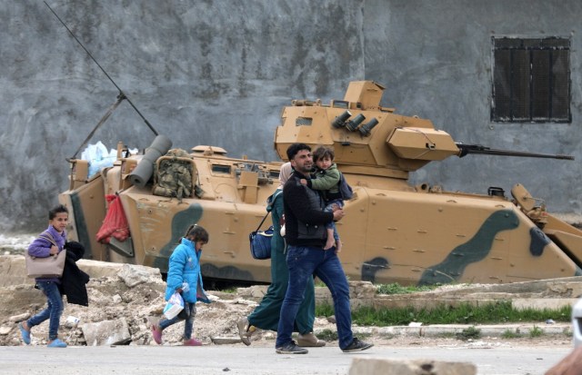 A family walks past a military vehicle belonging to Turkish-backed Free Syrian Army fighters after the capture of Khaldieh village, in eastern Afrin, Syria March 10,2018. REUTERS/ Khalil Ashawi
