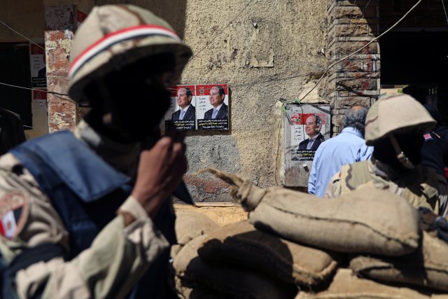 Members of security forces stand guard as posters of Egypt's President Abdel Fattah al-Sisi are pictured in the background during the presidential election in Cairo, Egypt March 26, 2018. REUTERS/Ammar Awad