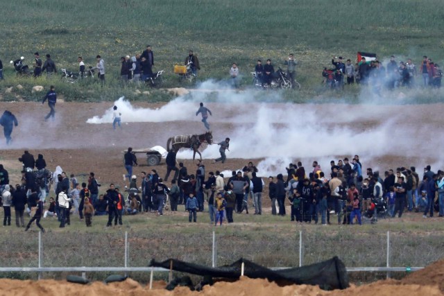 Palestinians run from tear gas on the Gaza side of the Israel-Gaza border, as seen from the Israeli side of the border, March 30, 2018. REUTERS/Amir Cohen
