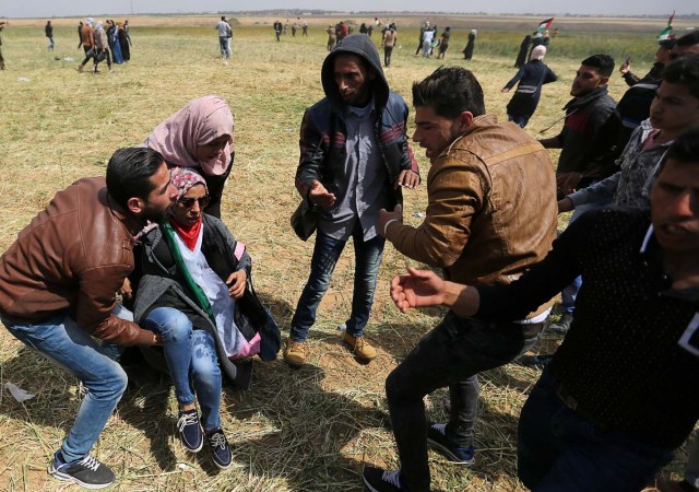 A wounded Palestinian woman is evacuated during clashes with Israeli troops, during a tent city protest along the Israel border with Gaza, demanding the right to return to their homeland, the southern Gaza Strip March 30, 2018. REUTERS/Ibraheem Abu Mustafa