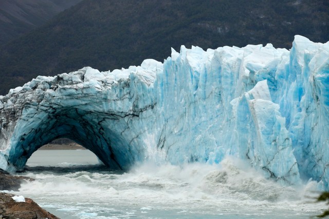 Chuncks of ice come off from the Perito Moreno Glacier, at Los Glaciares National Park, near El Calafate in the Argentine province of Santa Cruz, on March 11, 2018. An arch of ice formed at the tip of the Perito Moreno, between the glacier and the shore of Argentino lake, started collapsing into the water on Saturday, a natural display that happens just once every several years. Such arches form roughly every two to four years, when the glacier forms a dam of ice that cuts off the flow of water around it into the lake -- until the water breaks through, opening up a steadily wider tunnel that eventually becomes a narrow arch... and then collapses. / AFP PHOTO / Walter Diaz