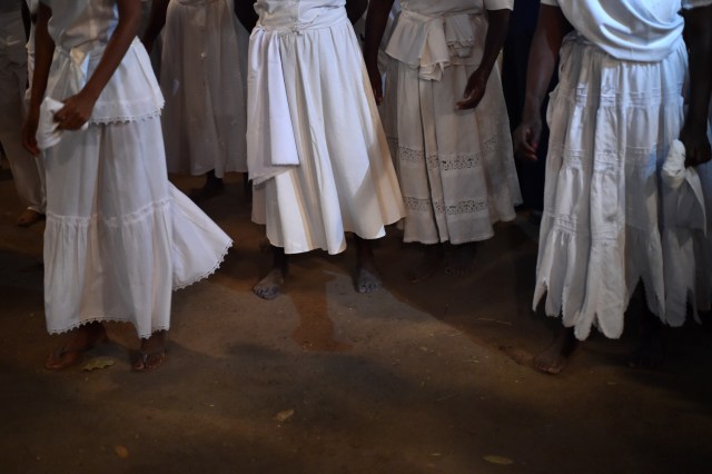 Haitian voodoo followers wearing white clothes dance while participating in a voodoo ceremony in Souvenance, a suburb of Gonaives, 171km north of Port-au-Prince, on March 31, 2018. Haitian voodoo followers arrived in Souvenance to take part in the voodoo ceremonies held during Easter weekend. / AFP PHOTO / Hector RETAMAL