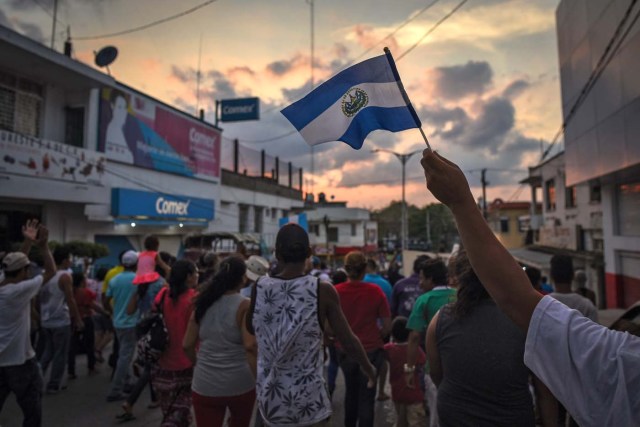 A migrant -alongside other Central Americans taking part in a caravan called "Migrant Viacrucis" towards the United States- flutters a Guatemalan national flag during a march to protest against US President Donald Trump's policies in Matias Romero, Oaxaca State, Mexico, on April 3, 2018. The hundreds of Central Americans in the "Way of the Cross" migrant caravan have infuriated Trump, but they are not moving very fast -- if at all -- and remain far from the US border. As Trump vowed Tuesday to send troops to secure the southern US border, the caravan was camped out for the third straight day in the town of Matias Romero, in southern Mexico, more than 3,000 kilometers (1,800 miles) from the United States. / AFP PHOTO / VICTORIA RAZO
