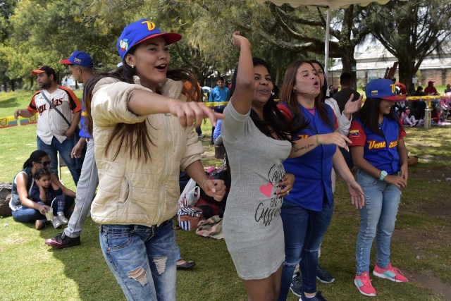 Venezuelan immigrants cheer for their team during the inauguration of the Pichincha League Softball Championship, at Parque Bicentenario, in Quito on March 18, 2018. The increase in the number of Venezuelan immigrants in Ecuador leaded to growth of the softball league from four to 16 teams in the last years, with some 450 players in total. / AFP PHOTO / Rodrigo BUENDIA / TO GO WITH AFP STORY BY PAOLA LOPEZ