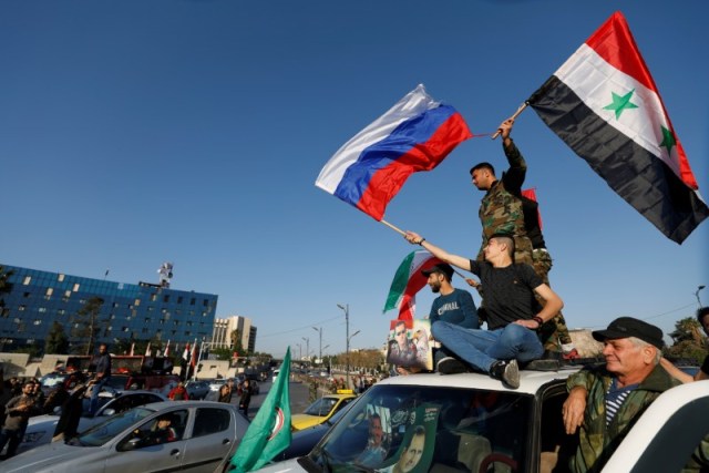 Syrians wave Russian and Syrian flags during a protest against U.S.-led air strikes in Damascus,Syria April 14,2018.REUTERS/ Omar Sanadiki - RC1A0FAE5590