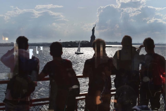 People ride the Staten Island Ferry while looking at the Statue of Liberty, in New York City, on April 28, 2018. / AFP PHOTO / HECTOR RETAMAL