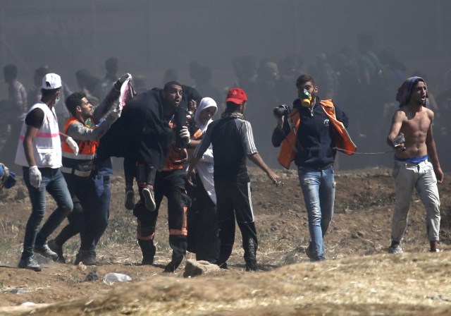 Los palestinos llevan a un manifestante herido durante enfrentamientos con fuerzas israelíes cerca de la frontera entre Gaza e Israel al este de la ciudad de Gaza el 14 de mayo de 2018, mientras los palestinos protestan por la inauguración de la embajada de Estados Unidos tras su controvertido traslado a Jerusalén. Docenas de palestinos fueron asesinados por disparos israelíes el 14 de mayo cuando decenas de miles protestaron y estallaron enfrentamientos a lo largo de la frontera de Gaza contra la transferencia de su embajada a Jerusalén, luego de meses de protestas globales, ira palestina y elogios exuberantes de los israelíes por el presidente Donald Trump decisión dejando de lado décadas de precedentes. / AFP PHOTO / Thomas COEX