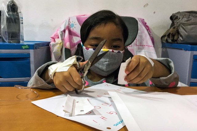 A girl plays as she receives chemotherapy at the "Dr. JM de los Rios" Children's Hospital in Caracas on April 10, 2018. The crisis in Venezuela has hit children's health, with an increase of 30,12% in child mortality according to the most recent official sources. / AFP PHOTO / FEDERICO PARRA